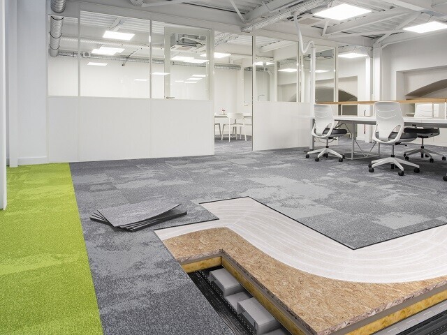 Office space with carpet tiles which are partly removed to show the underfloor