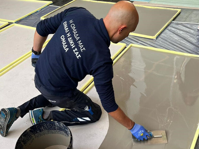 Guy applying flooring adhesive to a substrate 